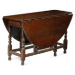 A Queen Anne oak gateleg table, the oval drop-leaf top above a frieze drawer to either end, on