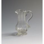 A small glass cream jug c.1750-60, the slender baluster form moulded with vertical flutes above a