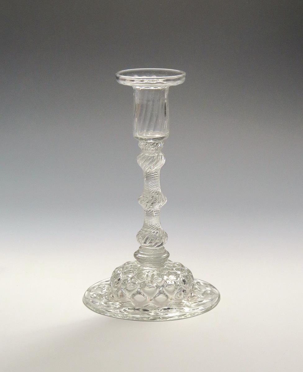 A glass candlestick c.1750, with a pan-topped moulded nozzle above a multi-knopped airtwist stem