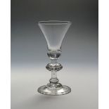 A heavy baluster wine glass c.1720, the wide bell bowl enclosing a small tear to the base, above