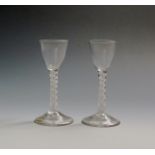 A pair of wine glasses c.1760-70, with small round funnel bowls raised on mixed twist stems, an