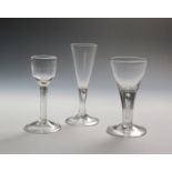 Three wine glasses c.1750-60, two with drawn trumpet bowls rising from plain stems enclosing