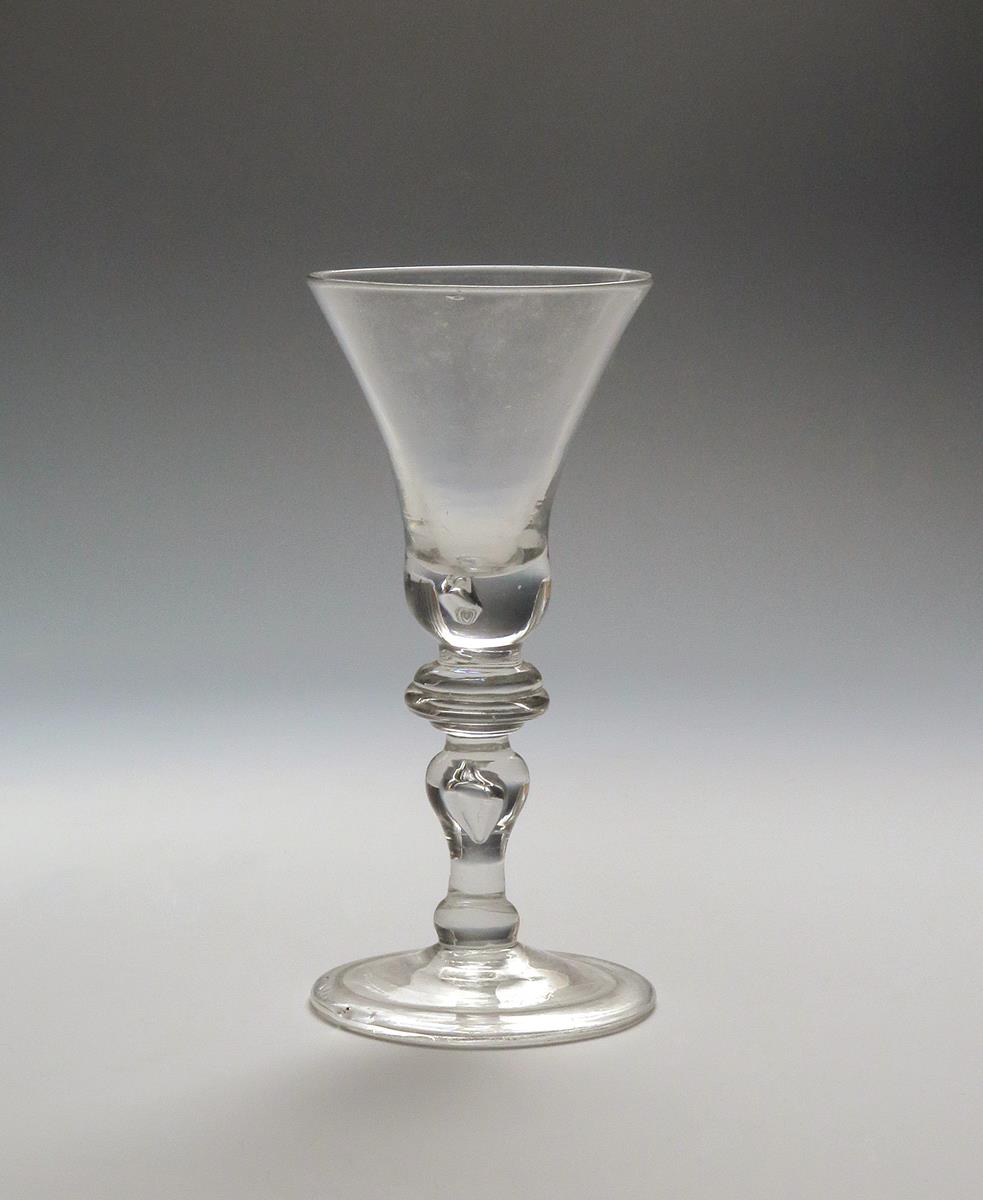 A baluster wine glass c.1720, the bell bowl with a tear to the base, above an annulated knop and