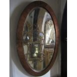 An Arts & Crafts wall mirror of oval form with bevelled edge plate and copper clad surround, 85 cm x