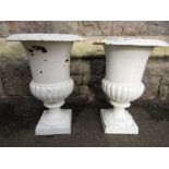 A pair of cast iron campana shaped urns with flared foliate patterned rims and square cut bases,