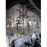 A glass chandelier with ten scrolling branches, faceted lustre drops and flower head detail