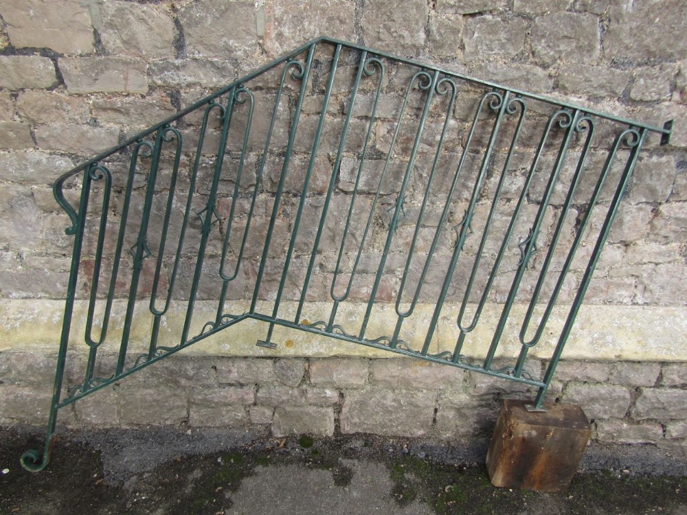 An iron work step rail with simple scroll detail and green painted finish