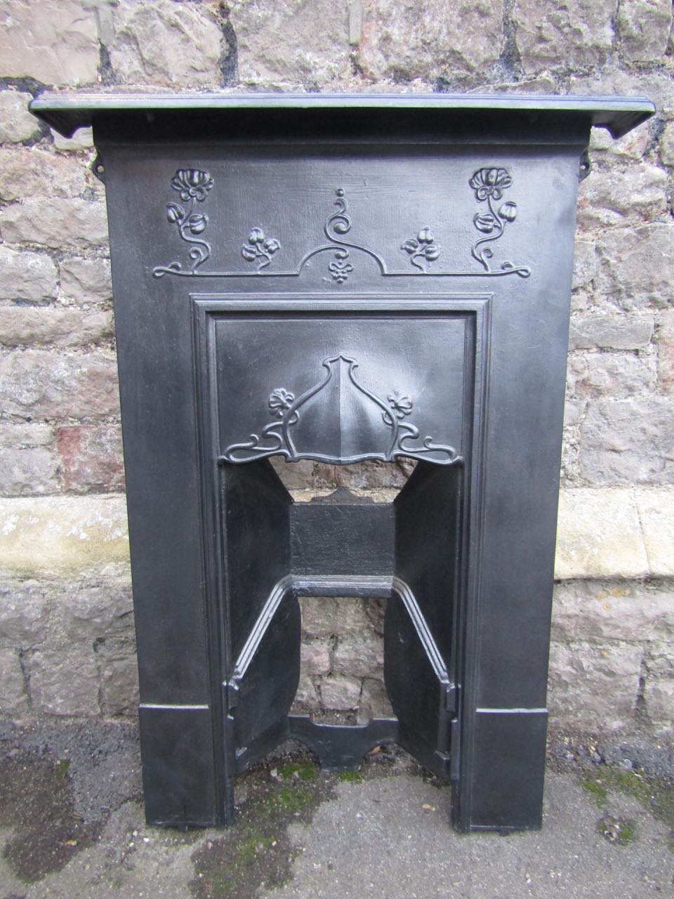 An Edwardian cast iron fire insert/grate with scrolling Art Nouveau style foliate detail, 70 cm wide