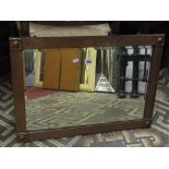 An Arts & Crafts style wall mirror of rectangular form with bevelled edge plate and copper clad