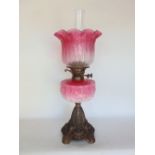 A late 19th century oil lamp with pink glass shade decorated with scrolled foliage and further