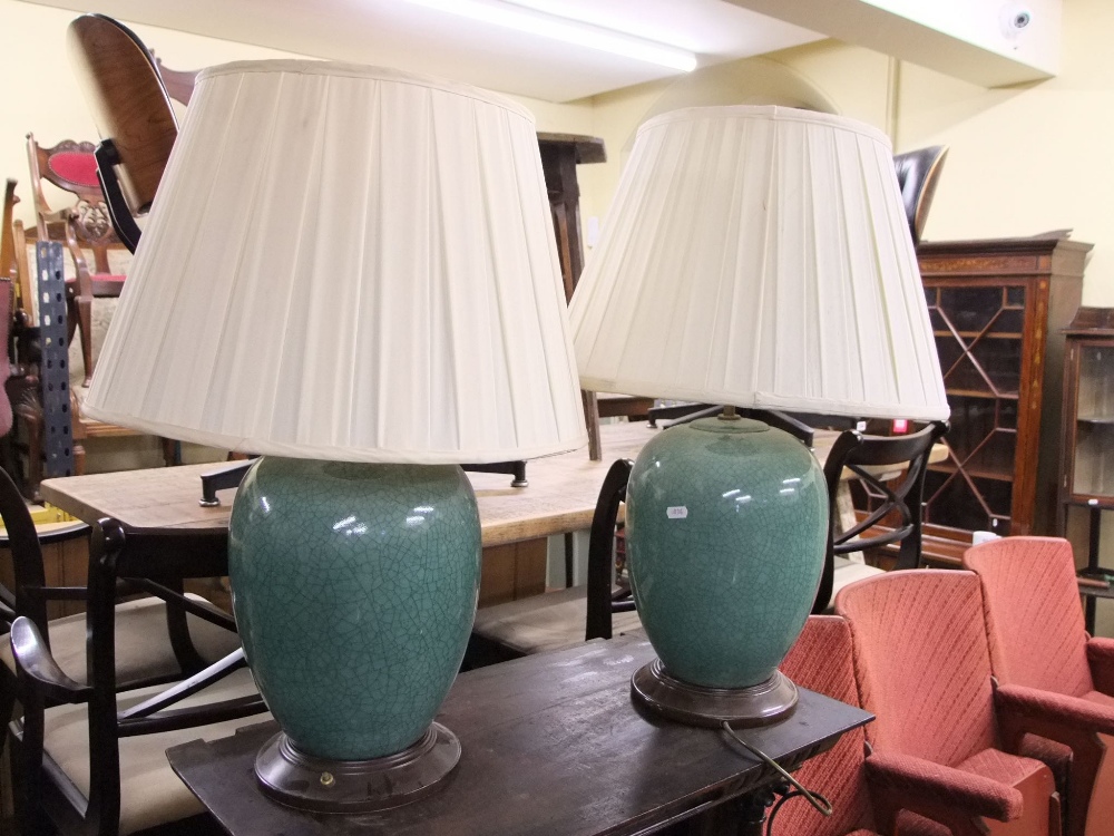 A pair of Chinese style celadon glazed oviform vases presented as table lamps, raised on turned