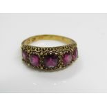 A Victorian 18ct ruby ring set with five graduating claw set stones, in pierced and engraved