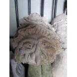 A weathered carved natural stone head in the form of a witch with well defined features and bonnet