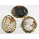 Two cameo brooches together with a further brooch set with polished agate, each in yellow metal