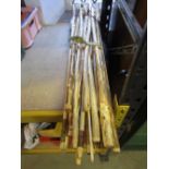 A bundle of approximately 20 rustic walking sticks with varnish finish