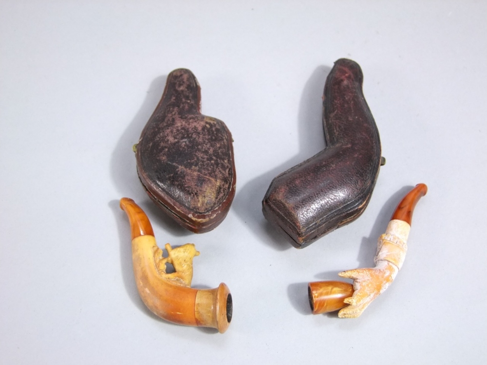Two 19th century Meerschaum cheroot holders, both cased, a hand clasping a beaker and a startled
