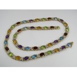 A diamond and gem set necklace marked 750, stones to include garnets, citrines and amethysts, 27g