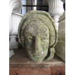 A reclaimed and weathered carved natural stone corbel with well defined female face mask with