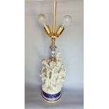 A French bisque porcelain figural table lamps with twin lights fitting over a rich figural group