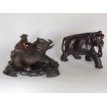 Two Japanese hardwood carvings, one of an elephant the other with a boy on the back of a water