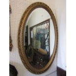 An oval wall mirror with bevelled edge plate within a moulded gilt frame with pierced scrolling