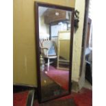 A mirror of rectangular form with stepped and moulded mahogany veneered frame, 122 cm x 50 cm