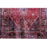Persian carpet decorated with geometric floral patterns around a blue medallion upon a red ground,
