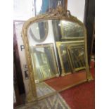 A Victorian overmantle mirror with bevelled edge plate within a moulded gilt arched frame with