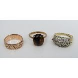 Three 9ct rings including a claw set tigers eye example and an engraved wedding ring, K/L, N & K, 9g