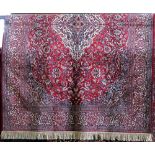 Persian style silk rug, decorated with a scrolled blue and cream foliage upon a red ground, 220 x