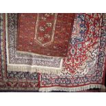 Four various Persian type rugs, the largest decorated with geometric scrolled foliage upon a blue