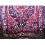 Persian style floor rug with central floral medallion and further geometric icons upon a red and