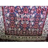 Persian wool runner decorated with geometric pink floral patterns upon a navy blue ground with cream