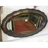 An Edwardian wall mirror of oval form, with bevelled edge plate, ebonised beaded slip and moulded