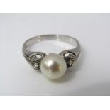 An 18ct white gold ring in the art deco style, set with a large pearl and diamonds to the shoulders,