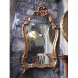 A shield shaped, gilt framed wall mirror, with moulded outline and C scroll and acanthus detail,