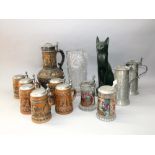 A mixed collection of various ceramic and glass steins, many with metal lids and thumb pieces,