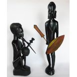 Two African carved tribal figures, one of a man holding his spear, the other playing an