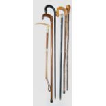 A collection of five walking canes to include a silver topped example and further exotic wood