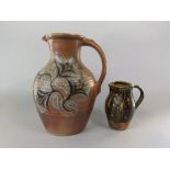 A large studio pottery type earthenware jug with painted stylised floral and leaf decoration in