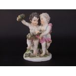 A 19th century Vienna porcelain group of a pair of cherubs holding floral cornucopia and floral