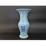 An oriental vase of baluster shaped form with blue and white painted trailing foliate detail and