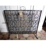An ironwork fireguard with wire mesh and entwined C scroll panel