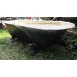 A reclaimed Victorian cast iron roll top bath, with single rounded end of tapered form raised on