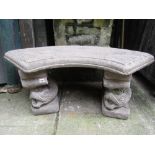 A weathered composition stone three sectional garden bench with curved slab seat raised on a pair of