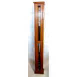 Ships barometer thermometer, upon a black and steel cylinder frame, within a glazed beech cabinet,