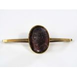 A 9ct bar brooch set with a carved amethyst depicting the profile of a gentleman, probably