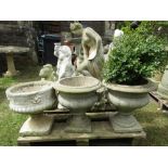 A pair of cast composition stone urns of circular form, together with two further pedestal urns of
