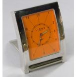 Links of London silver plated travel alarm clock, the bright orange dial with Arabic, within an