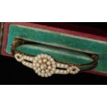 A seed pearl encrusted hinged bangle with diamond set flower head motif, the diamond 0.20cts approx,